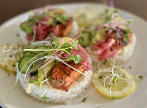 Salmon stacks with sushi rice, avocado, cucumber, microgreens, and broccoli sprouts.