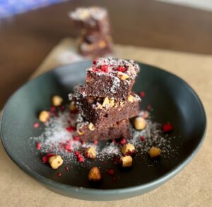 Fudgy chocolate brownies made with Eatmore Mixed Beans, chocolate chips, and hazelnuts, dusted with icing sugar.