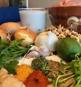 Ingredients for chicken korma including onions, garlic, spices, coconut milk, lime, fresh herbs, and Eatmore Mixed Beans.