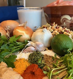 Ingredients for chicken korma including onions, garlic, spices, coconut milk, lime, fresh herbs, and Eatmore Mixed Beans.