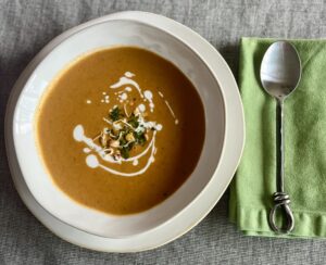 Creamy curried mixed bean and lentil tomato soup garnished with coconut milk, cilantro, and Eatmore Mixed Beans.