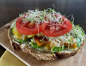Sourdough sandwich with roasted marinated peppers, avocado, tomato and Eatmore Sprouts.