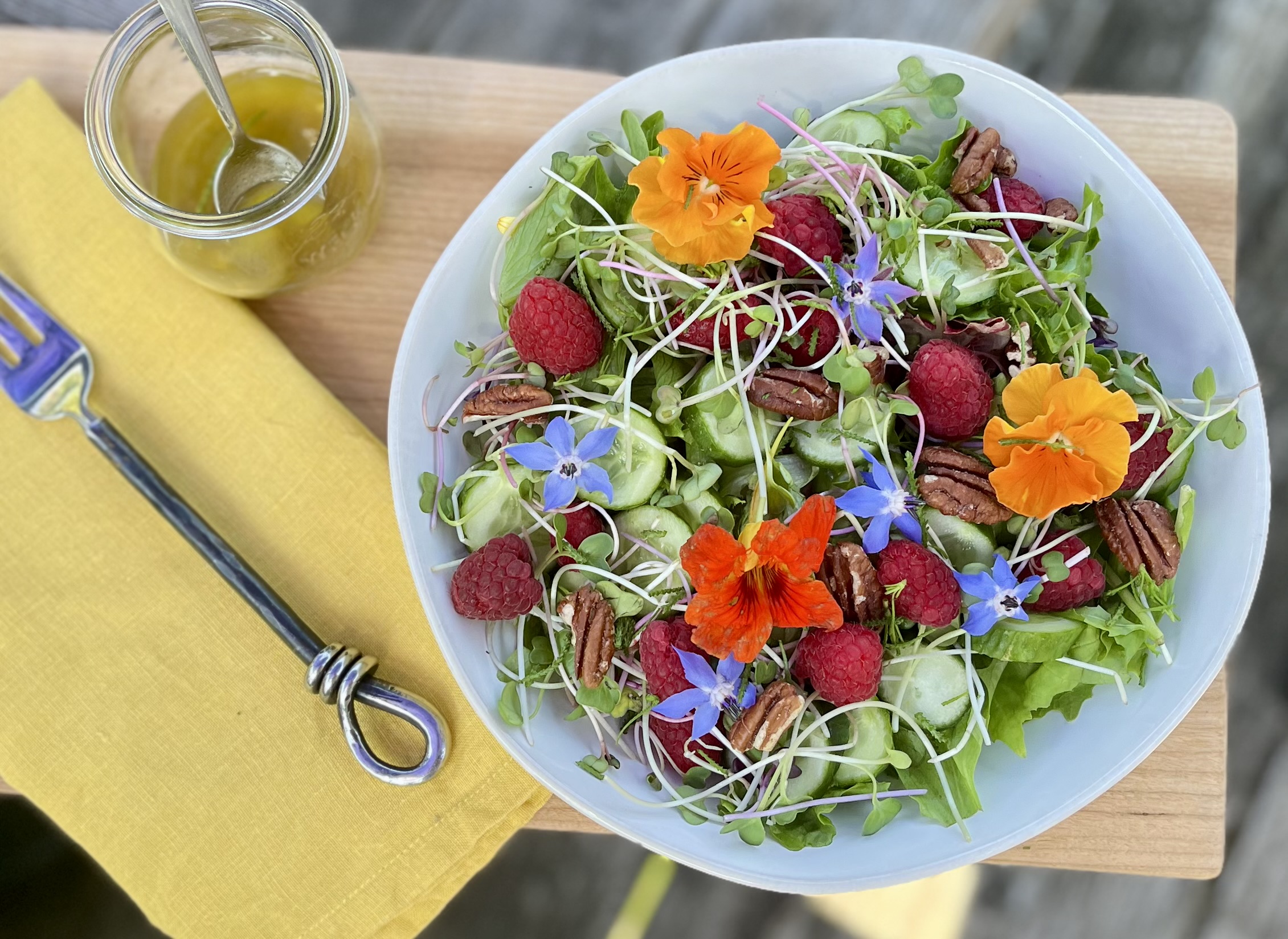 Summer salad with raspberries, cucumber, edible flowers and Eatmore Sprouts served with basil lemon vinaigrette.