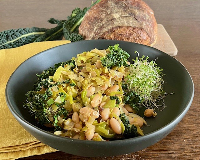 White bean and kale bowl with sautéed leeks, alfalfa sprouts, and sliced almonds.