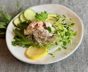 West Coast salmon lettuce wrap topped with Eatmore Deli Blend, pea shoots, avocado, cucumber, and lemon.